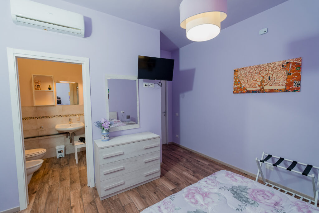 Cassettiera in legno chiaro con specchio e TV nella stanza Glicine