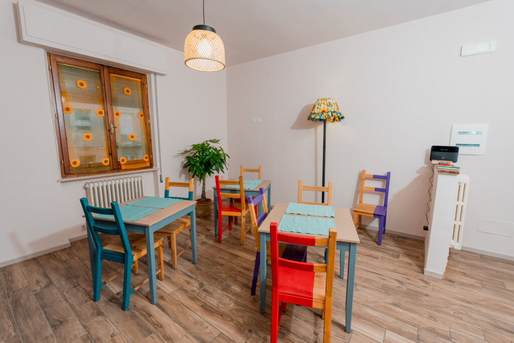 Zona giorno con tavoli e sedie colorate, lampada decorativa e finestra